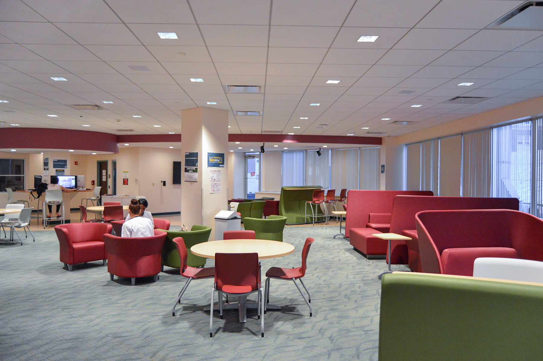 Quincy College student center seating area with tables and couches
